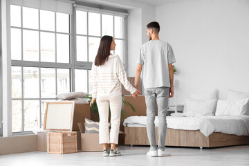 Young couple holding hands in bedroom on moving day, back view