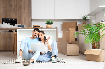 Young couple with laptop video chatting in kitchen on moving day