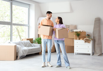 Young couple with cardboard boxes in room on moving day