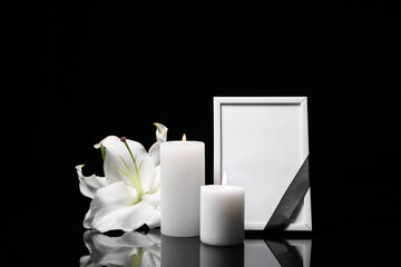 Blank funeral photo frame, candles and lily on black background