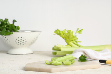 Board with cut fresh green celery on white background