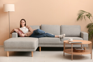 Obraz premium Young woman lying on sofa in stylish living room