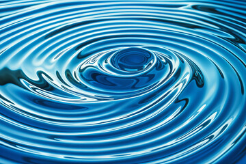 A close-up view of rippling blue water, with the focus on a circular pattern created by the waves.