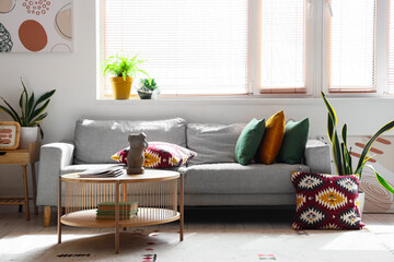Grey sofa, pillows, coffee table and houseplants in light living room