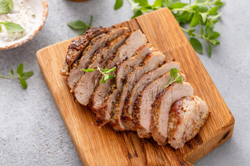 Grilled pork chop sliced on a cutting board with herbs
