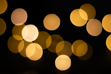 Blurred yellow christmas lights on black background. Yellow light bulbs.
