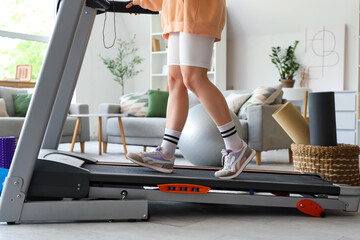 Sporty woman jogging on treadmill at home