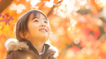 Fototapeta premium 美しい秋の紅葉を見上げて微笑む子ども