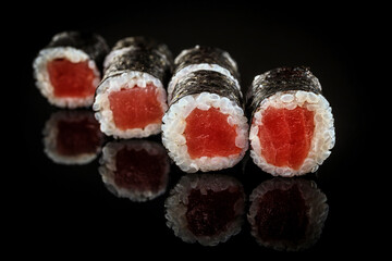 Sushi roll with tuna, on a black mirror
