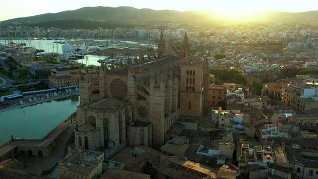 Palma de Mallorca Cathedral Cinematic Aerial Orbit at Sunset, La Seu Gothic Basilica with Golden Sun Flares in Camera, Majestic Spanish Landmark in Evening Light, Balearic Islands Spain 4K Video