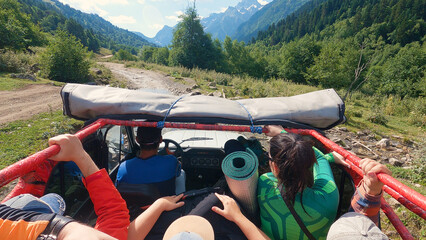 Outdoor Excursion. A group of people in an off-road vehicle, wearing outdoor clothing, set out to find adventure in a lush mountainous area.
