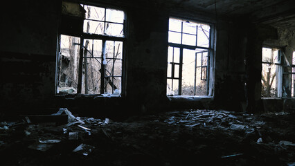 Abandoned, dilapidated building with broken windows and debris scattered on the floor. The light...