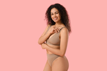 Beautiful young happy African-American woman in stylish underwear on pink background