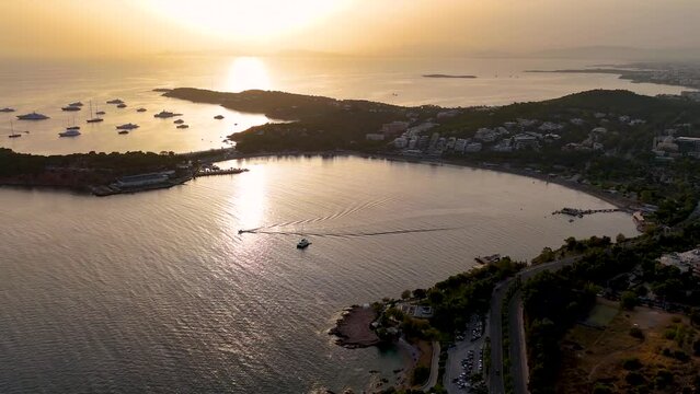 Establishing aerial view of the bay and beach of Vouliagmeni, south Athens, reece, during a golden summer sunset