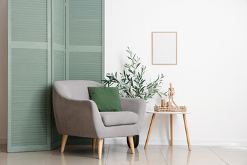Interior of beautiful living room with grey armchair, coffee table and olive tree