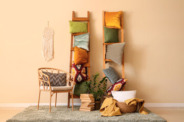 Armchair and ladders with soft pillows near beige wall in room