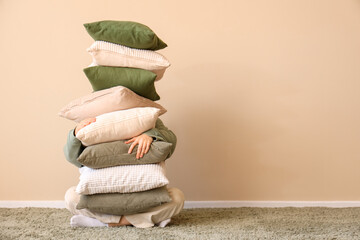 Young woman with stack of soft pillows in stylish room
