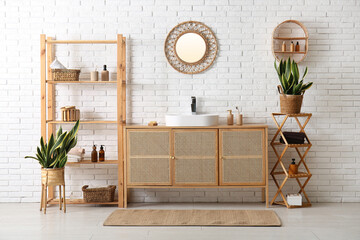 Ceramic sink, shelving unit and chest of drawers near white brick wall in stylish bathroom