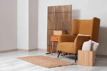 Stylish interior of living room with brown armchair, coffee table, pillow and folding screen