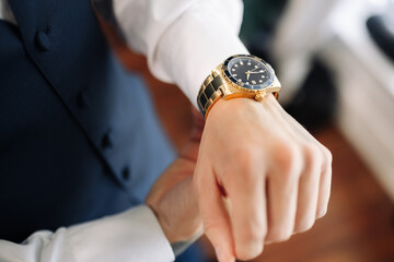A man puts a classic mechanical watch on his hand, close-up. A man's hand and a wristwatch close-up. Concept of punctuality and time management