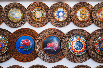 handmade Uzbek wooden gift plates with wood carvings hand-painted traditional patterns in the souvenir shop of Uzbekistan in Tashkent