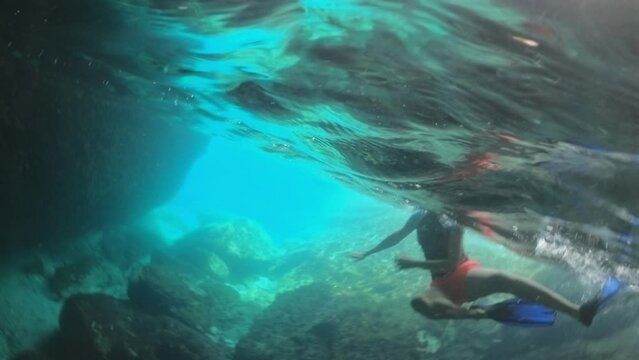 girl dives into the clear turquoise water of a serene cave pool with light reflections in the Blue Cave of Elba Island. Tuscan archipelago marine reserve of Italy, Enfola and Portoferraio cape.