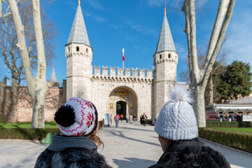 Obraz premium Mother and daughter with hats in the winter walking in the park and looking at the castle.