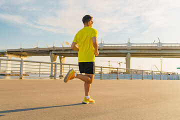 A guy in bright clothes – a T-shirt and some sneakers – is out running in the daytime.