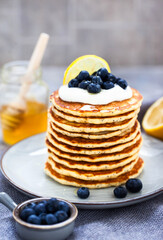 Stack of freshly prepared lemon poppy seed pancakes topped with sour cream and blueberries