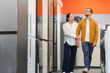 family couple buying domestic refrigerator in supermarket