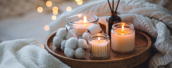 Burning candles, aroma fragrance organic reed diffuser, wooden bamboo tray. Concept of cozy home...