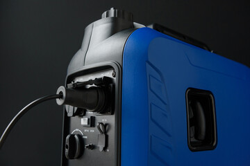 Close-up of the connected socket and generator ports. A modern portable gasoline inverter generator...