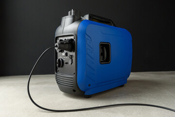 Connected generator. A modern blue portable gasoline inverter generator stands in a garage against...