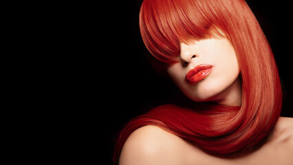 Beautiful model with healthy dyed red hair and stylish hairstyle against black background