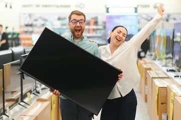 Young couple shopping at tech store. Buying new tv set for their home