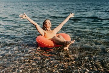A woman is floating in a red inflatable raft on a body of water