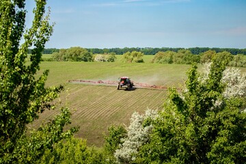 red sprayer spraying herbicide on soybean hilly field