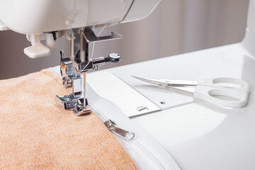 Modern sewing machine special presser foot with beige corduroy fabric and thread, closeup. Sewing...