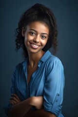 Fototapeta premium Smiling young woman in blue shirt posing confidently against dark background for professional portrait.