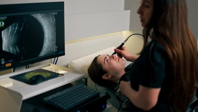 in an ophthalmology clinic young doctor performs an ultrasound of the eye of a young girl
