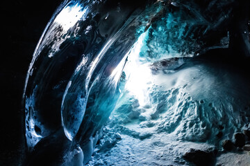 Mesmerizing ice cave amidst the dark landscape of the Bogdanovich Glacier in the Almaty Mountains...