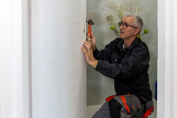 Installation of a lock on the wooden door. Carpenter installing lock handles in room door