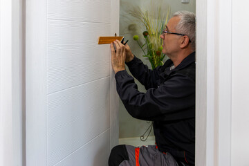 Installation of a lock on the wooden door. Angle square is used by carpenter to install lock handles in room door