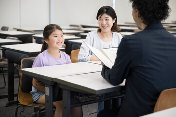 面談を受ける親と子供　小学校の教室での三者面談のイメージ