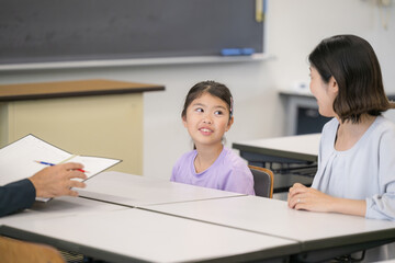 面談を受ける親と子供　小学校の教室での三者面談のイメージ