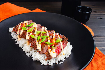 Korean Skirt Steak with Kimchi Aioli Over Jasmine Rice: Grilled skirt steak sliced and topped with aioli, gochugaru, scallions, and sesame seeds