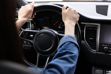 Woman holding steering wheel while driving her car, closeup