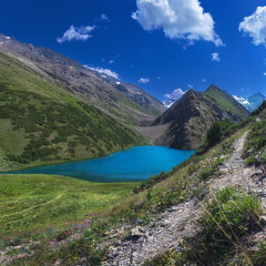 Lake with clear blue water in the mountains under the sky with clouds in summer