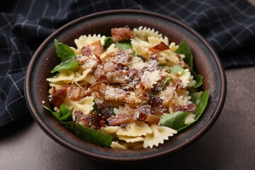 Tasty pasta with bacon and basil on brown table