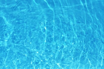 Blue water with ripples on the surface. Defocus blurred transparent blue colored clear calm water surface texture with splashes and bubbles. Water waves with shining pattern texture background.	